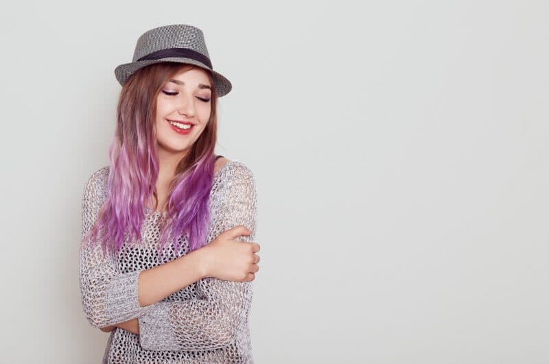 ย้อมผมครึ่งหัว - pleasant looking dreamy female with purple hair hugging herself keeping eyes closed expressing happiness copy space advertisement isolated white wall - ภาพที่ 3