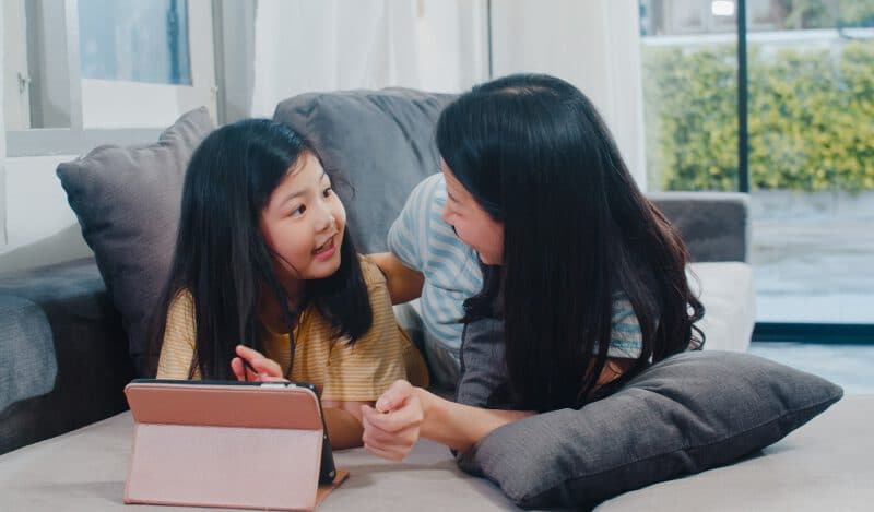 - young asian family daughter happy using tablet home japanese mother relax with little girl watching movie lying sofa living room house funny mom lovely child are having fun - ภาพที่ 13