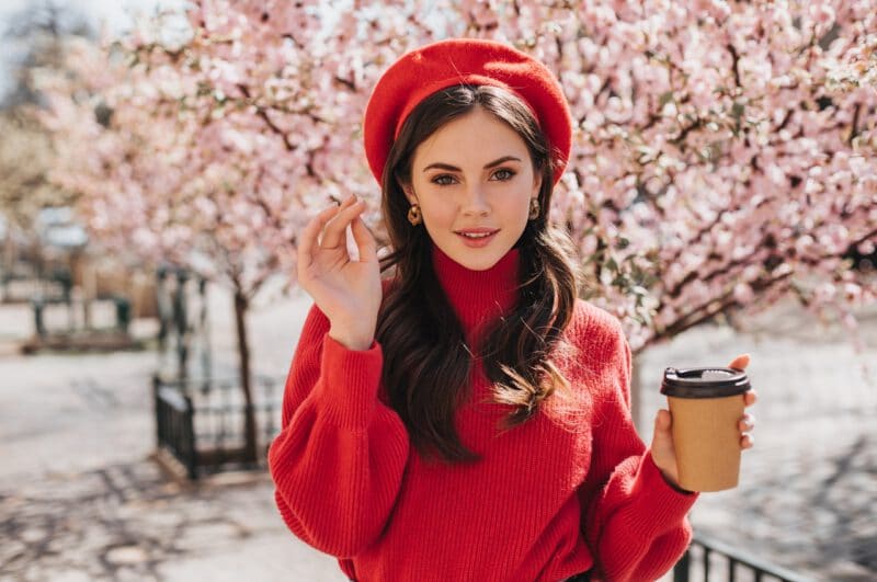 - attractive lady red sweater walks along avenue with sakura drinks coffee beautiful woman beret smiling enjoying tea outside - ภาพที่ 3