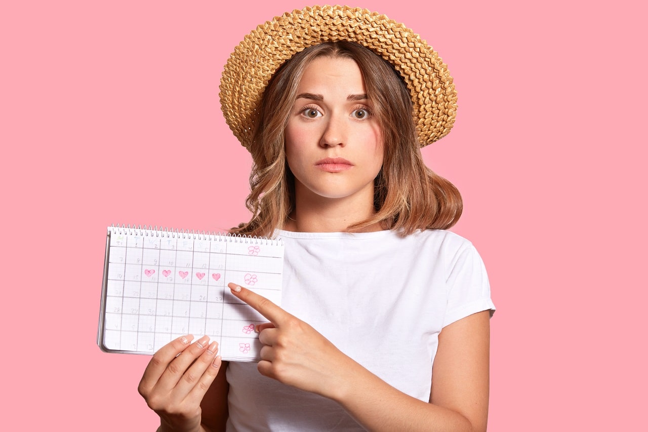 ประจำเดือน - woman with appealing look holds periods calendar checking menstruation days points with fore finger - ภาพที่ 3