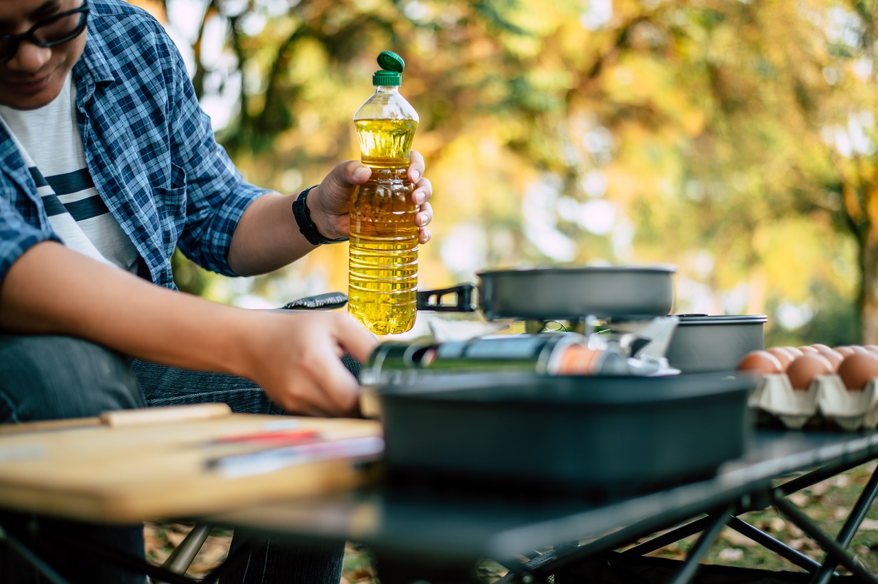 น้ำมันทอดซ้ำ - portrait thai traveler man glasses pouring sunflower oil into frying pan outdoor cooking traveling camping lifestyle concept - ภาพที่ 7