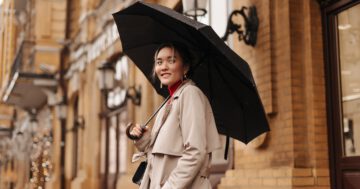 snapshot charming asian girl stylish trench coat holding black umbrella city street